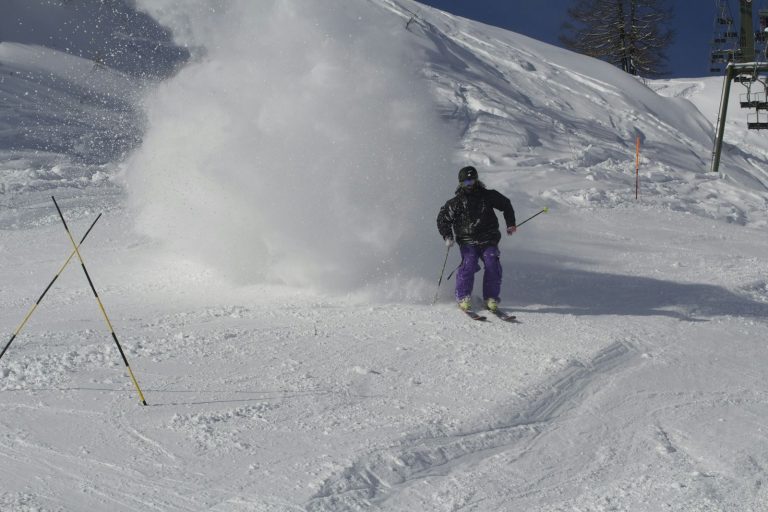 Skieur soulevant la neige sur une piste de Courmayeur, près d'un télésiège