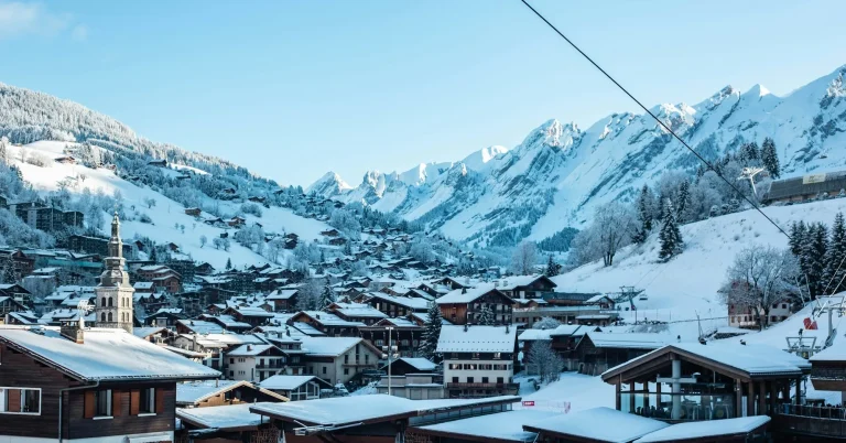 Le village enneigé de La Clusaz, son clocher et ses chalets, au cœur du massif des Aravis