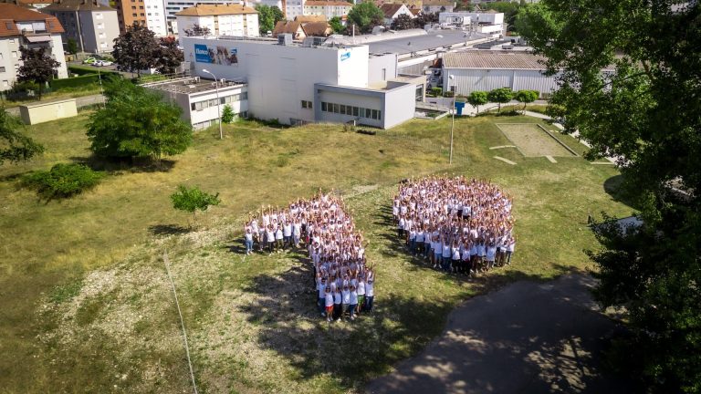 Aerial view of Elanco staff in white T-shirts forming a large 70 on the lawn in front of the production site, during the company’s annual sales retreat in Alsace