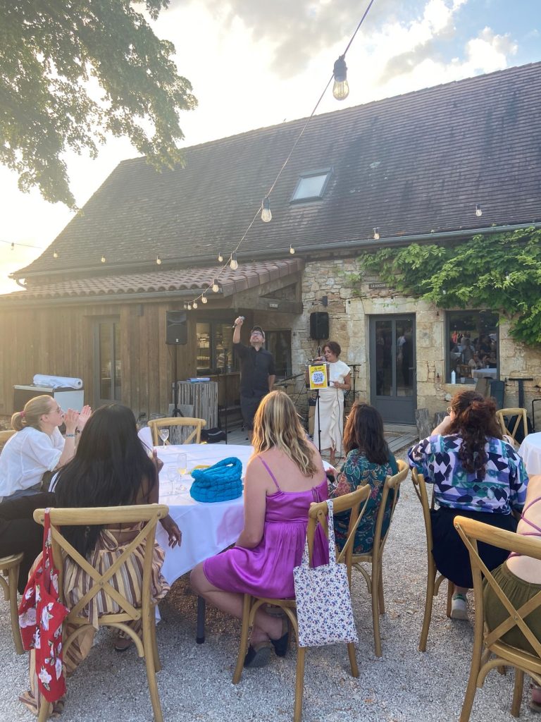 Karaoké live sur la terrasse du Domaine de Saint Amand au coucher du soleil, devant une bâtisse en pierre, pendant le séminaire résidentiel de HelloAsso