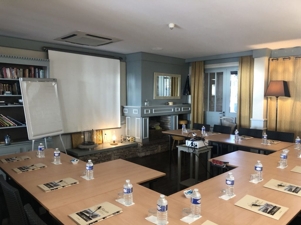 Salle de réunion de l’Hôtel de La Marée à Rivedoux-Plage, tables en U, écran, paperboard et vidéoprojecteur, préparée pour la matinée de travail du séminaire Swiss Life
