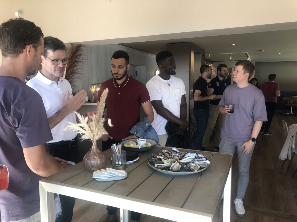 Participants du séminaire Swiss Life debout autour d’une table haute et d’un plateau d’huîtres, lors de la dégustation du dernier jour, à Rivedoux-Plage