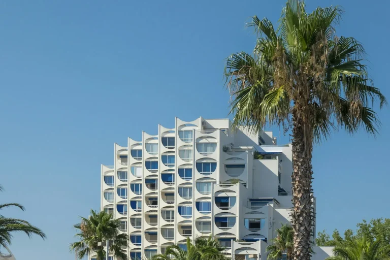 Un immeuble pyramide blanc de La Grande-Motte entre les palmiers, sous un ciel bleu