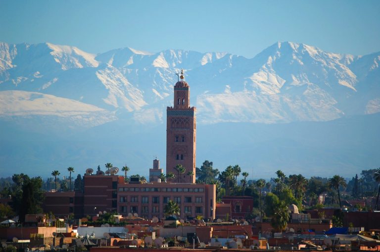 Le minaret de la Koutoubia et les toits de Marrakech, devant les sommets enneigés du Haut Atlas