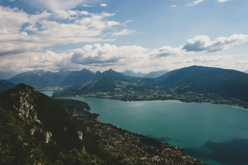 Le lac d’Annecy et ses rives vus des hauteurs, entre falaises boisées et montagnes