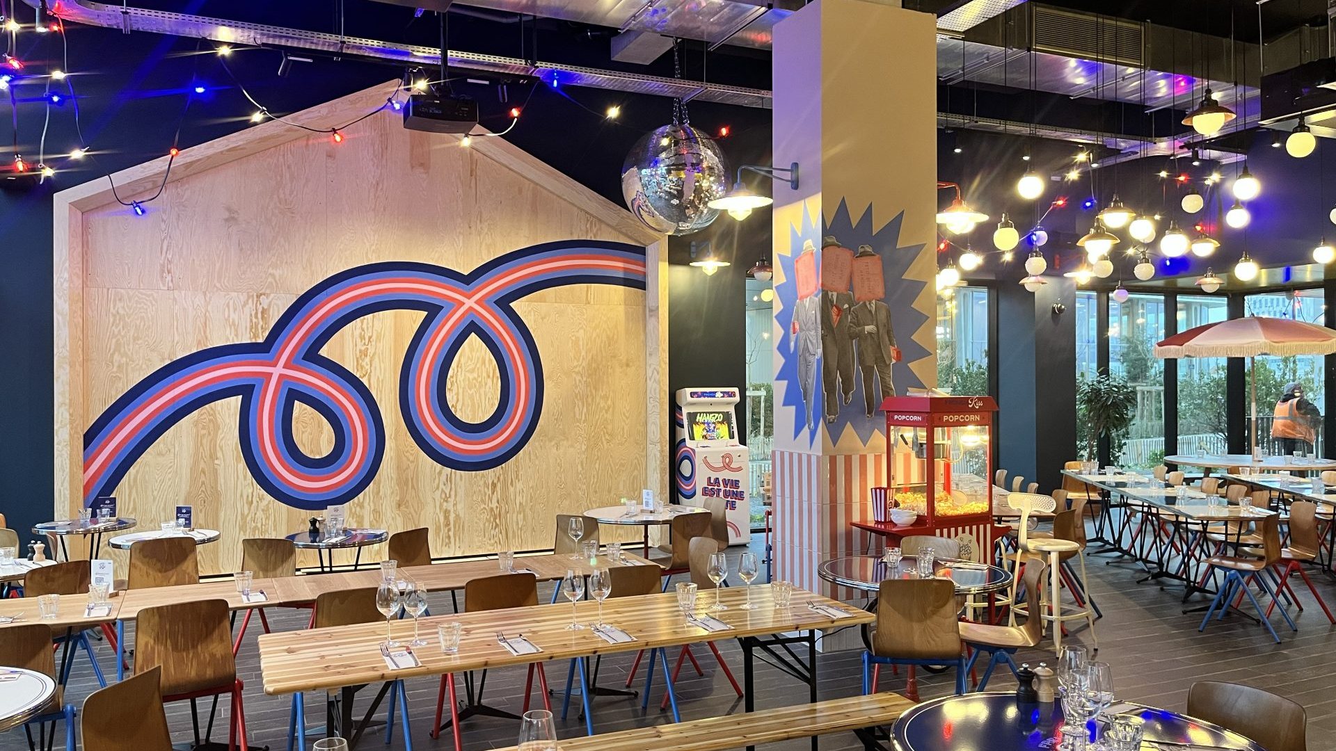 Restaurant de l'EKLO Hôtel de Nantes dressé de longues tables en bois, sous des guirlandes lumineuses et une boule à facettes, lieu choisi par Weevup pour réunir les équipes de Nantes et de Lyon d'ELO ÉNERGIE