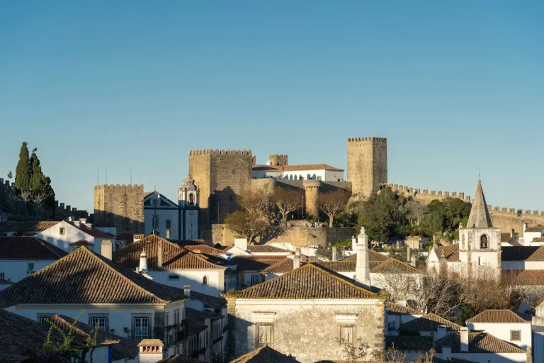 Le château médiéval d’Óbidos et ses remparts crénelés au-dessus des toits de tuiles et des maisons blanches de la ville, au Portugal