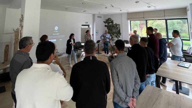 Participants du séminaire Pacific debout face à un écran, dans une salle lumineuse aux baies vitrées ouvertes sur la verdure, pendant un atelier au domaine de Ribiera, en Provence