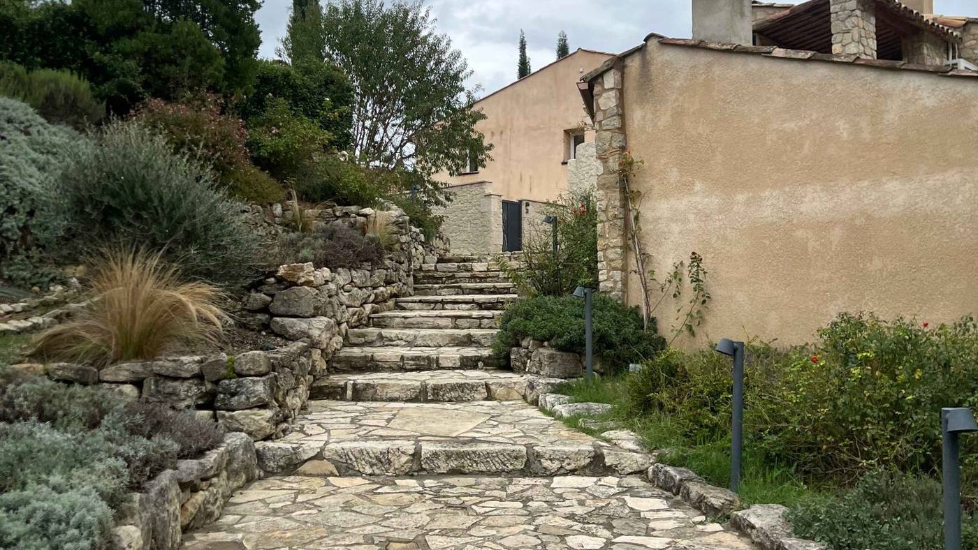 Escalier et allée en pierre bordés de plantes méditerranéennes et de cyprès, menant à une bâtisse provençale du domaine de Ribiera, lieu du séminaire Pacific organisé par Weevup