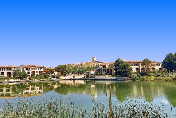 Bâtiments aux façades ocre et toits de tuiles du village de Pont Royal en Provence, reflétés dans un lac bordé de roseaux, lieu d'un séminaire de 200 personnes organisé par Weevup