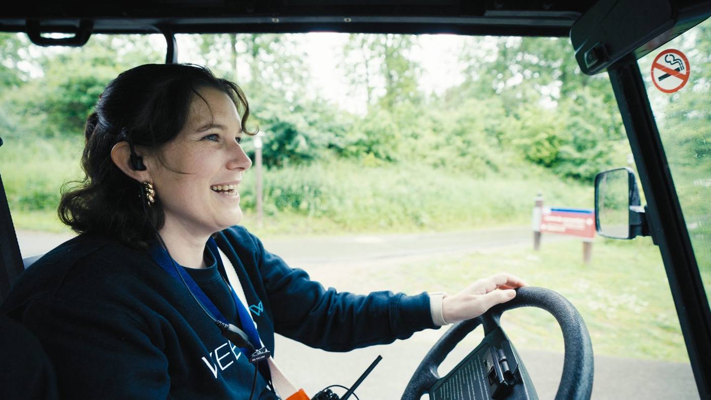 Membre de l'équipe Weevup souriante au volant d'une voiturette, dans les allées boisées du Center Parcs du Lac d'Ailette, pendant le séminaire KPMG