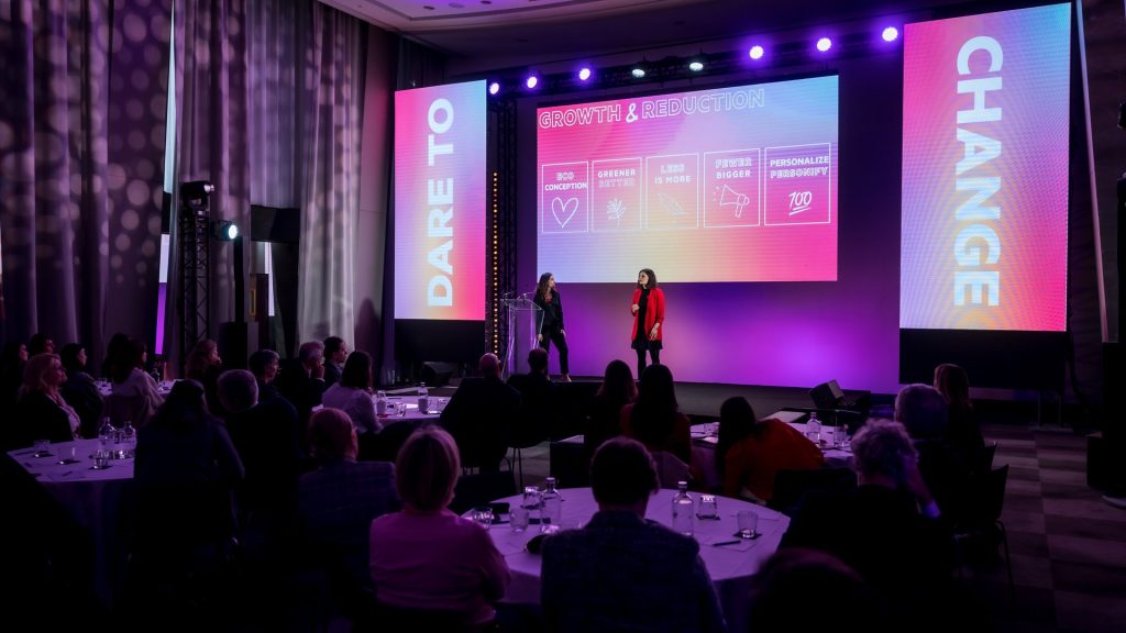 Plenary of SVR’s international seminar in Paris: two speakers on stage in front of a “Growth & Reduction” screen, between two side screens reading “Dare to” and “Change”, facing participants at round tables