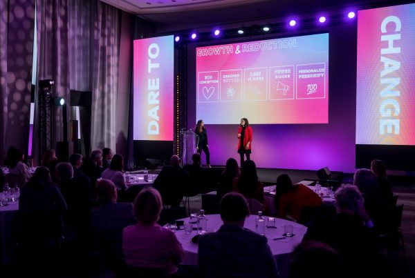 Plénière du séminaire international SVR organisé par Weevup : deux intervenantes sur scène devant un écran « Growth & Reduction », entre deux écrans « Dare to change », face aux participants installés en tables rondes