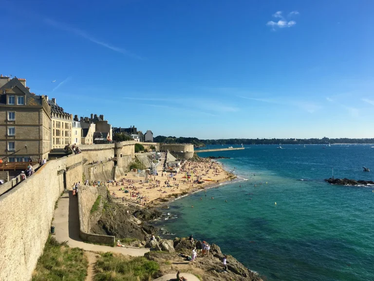 Les remparts de Saint-Malo longeant la plage, face à la mer, sous un ciel bleu