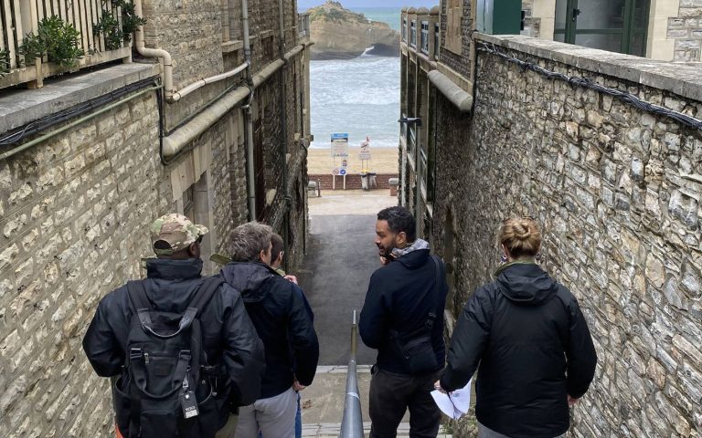 Participants de l’incentive de Libon dans une ruelle entre deux murs de pierre qui descend vers la plage de Biarritz, feuille de route en main