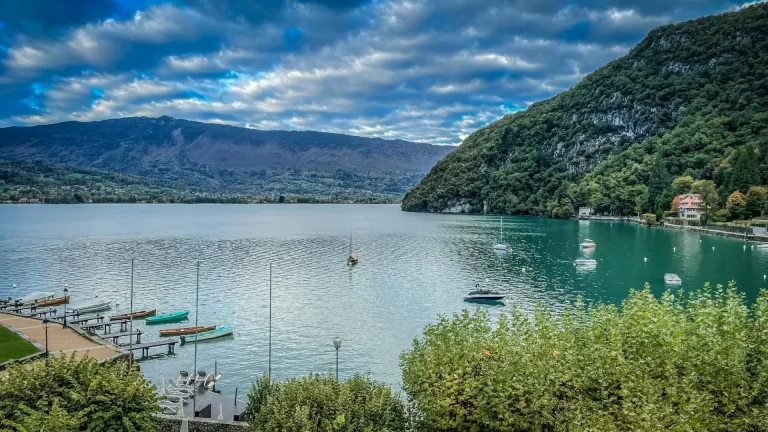 La baie de Talloires, ses pontons et ses bateaux sur le lac d’Annecy, au pied d’une montagne boisée