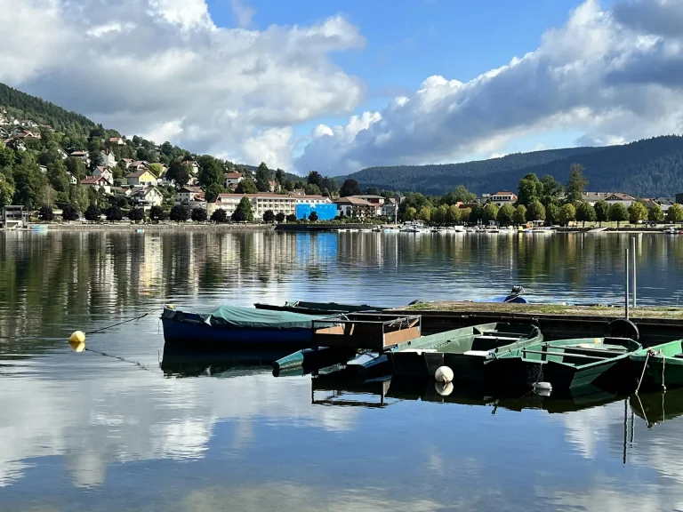Barques amarrées sur le lac de Gérardmer, avec la ville et les collines boisées des Vosges en arrière-plan