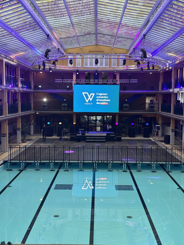 Bassin d’hiver du Molitor avant l’arrivée des invités de la soirée awards Scalian : plancher et garde-corps sur une partie du bassin, scène, écran LED et couronne de projecteurs sous la verrière