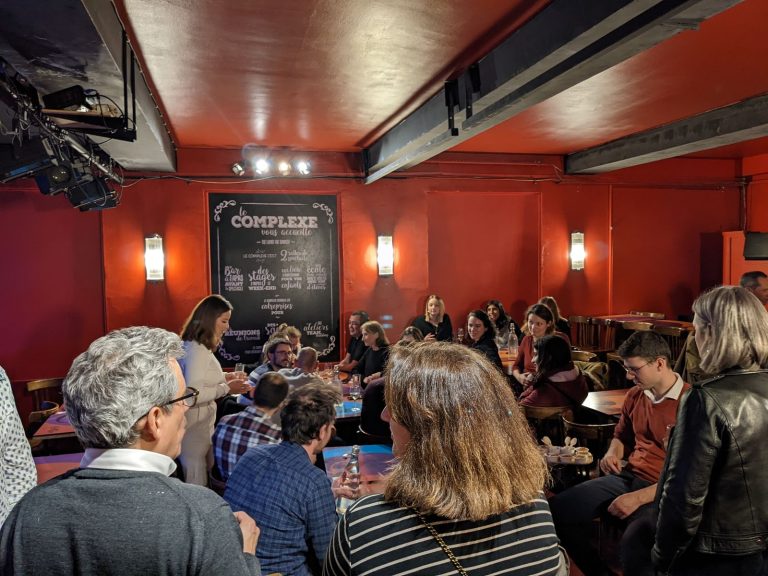 Invités de Tyredating attablés et debout, verre à la main, dans la salle du Complexe à Lyon, après le spectacle