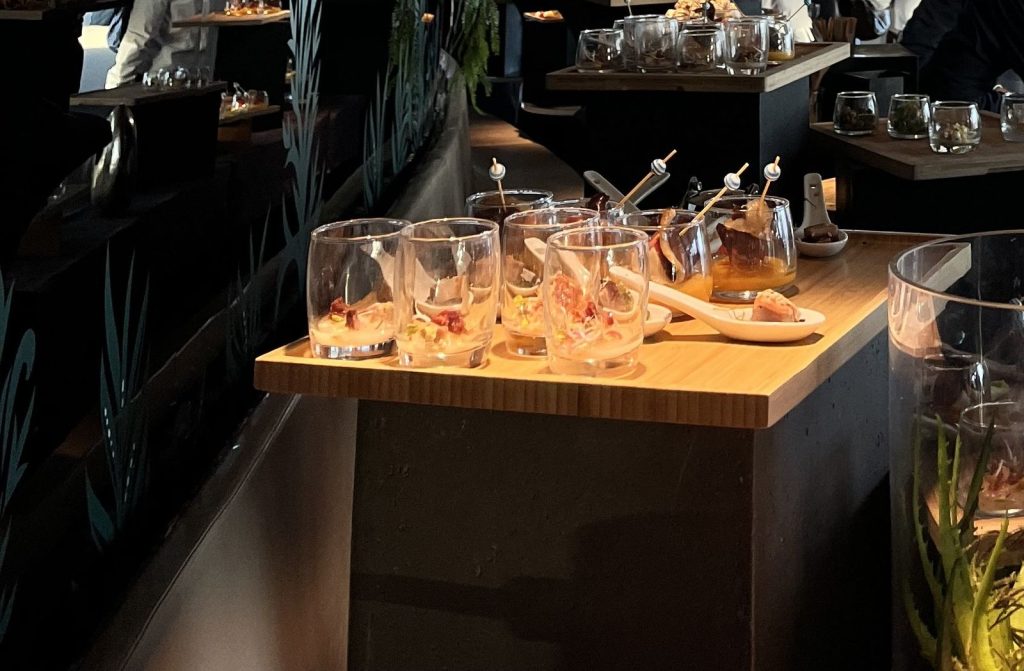 Verrines garnies, piques et cuillères apéritives du cocktail dînatoire sur un buffet en bois, au Skyline Bar du Meliá Paris La Défense