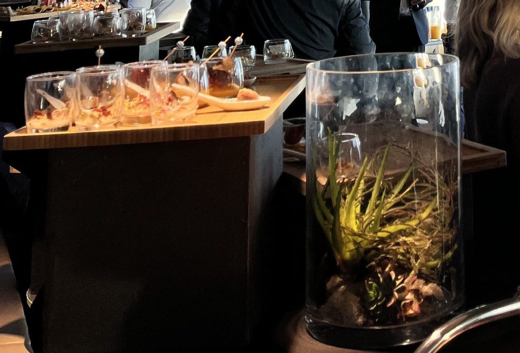 Verrines du cocktail dînatoire sur un buffet et terrarium de plantes en décor, au Skyline Bar du Meliá Paris La Défense
