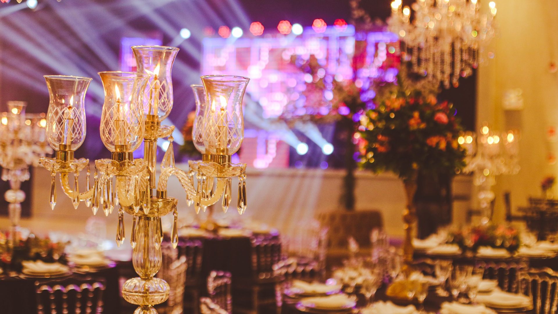 Salle de réception élégante dressée pour un dîner de gala d'entreprise, avec candélabres en cristal, tables rondes et éclairage de scène