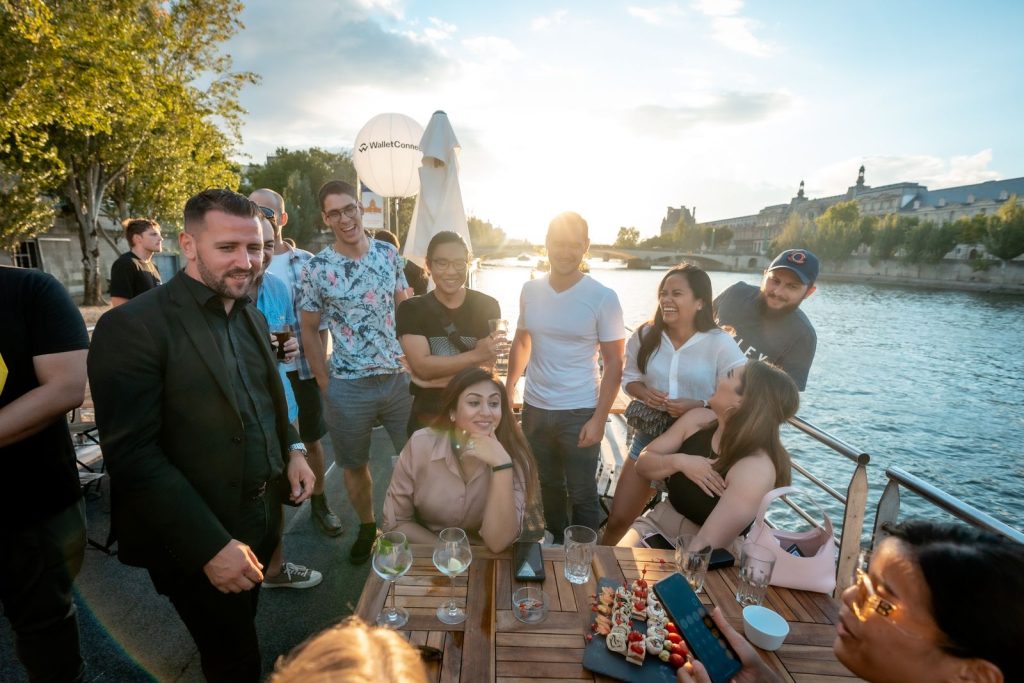 Soirée de lancement WalletConnect à La Balle au Bond : invités autour d’une table avec un plateau de pièces du cocktail, la Seine au soleil couchant