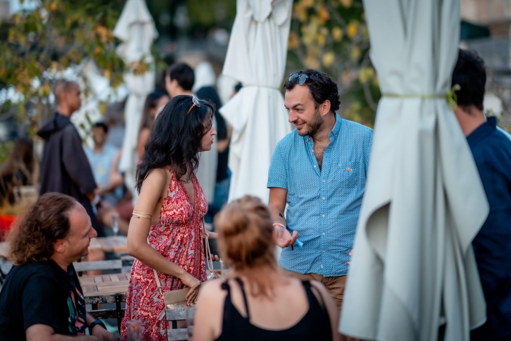 Soirée de lancement WalletConnect à La Balle au Bond : invités en conversation sur la terrasse de la péniche, entre les parasols repliés