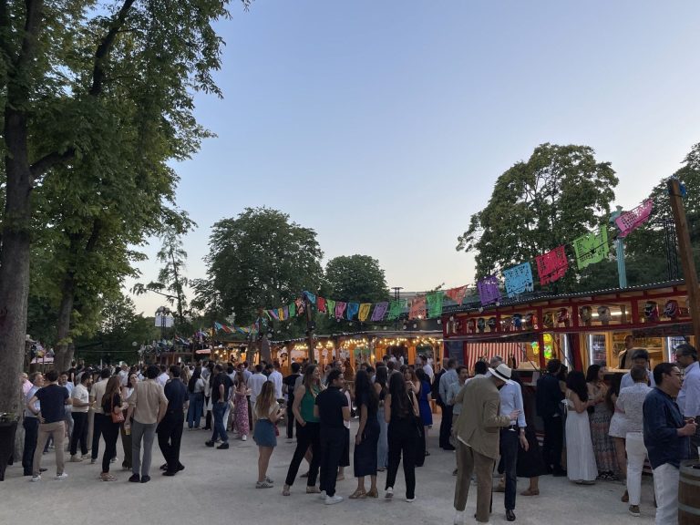 KPMG summer party on the summer terrace of the Aquarium de Paris at the end of the day, under colourful bunting, in front of wooden kiosks lit with fairy lights