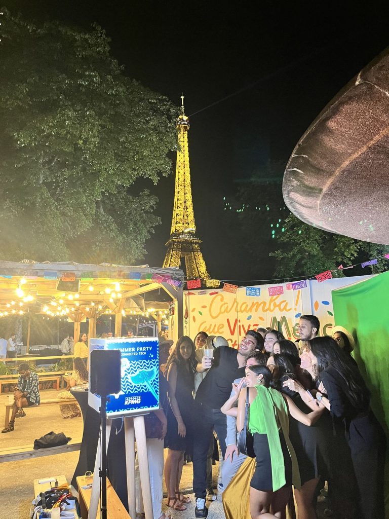 Summer Party KPMG à l’Aquarium de Paris : participants posant devant le fond vert de la borne photo, la tour Eiffel illuminée en arrière-plan