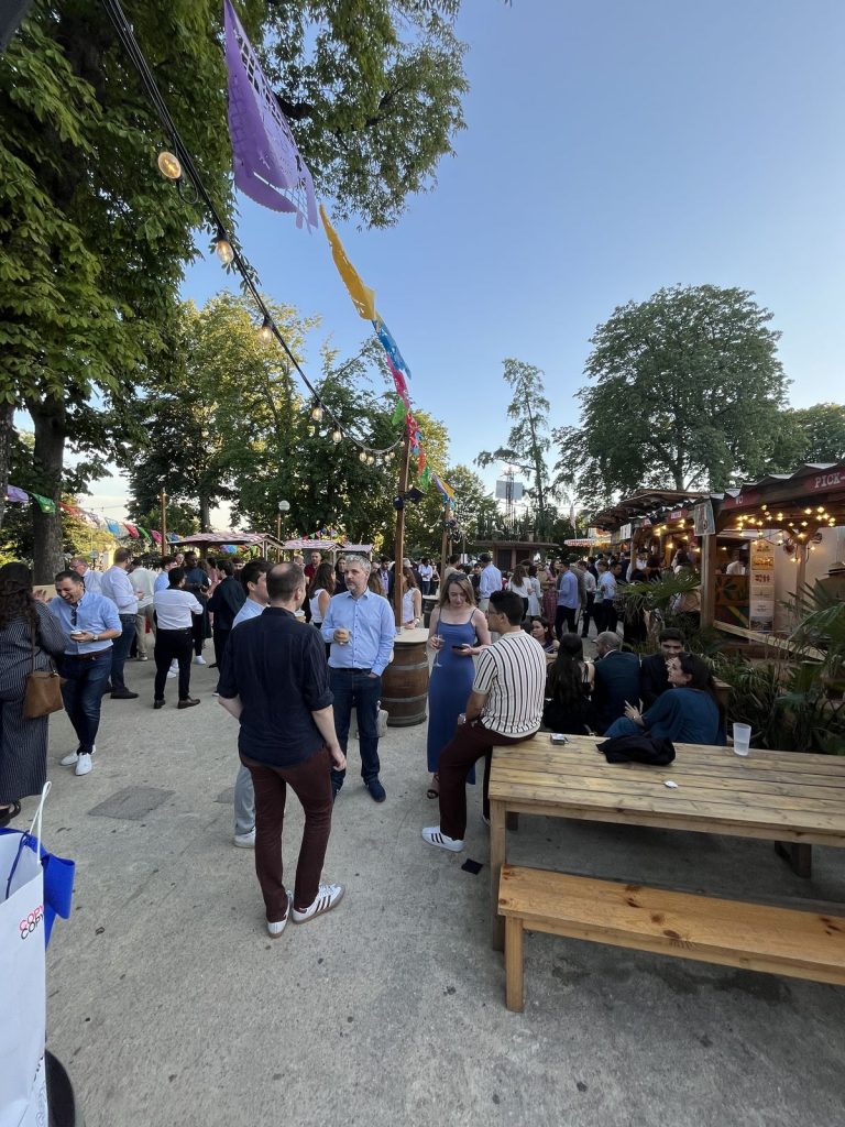 Summer Party KPMG à l’Aquarium de Paris : participants autour des tables en bois et des tonneaux de la terrasse, sous les guirlandes lumineuses