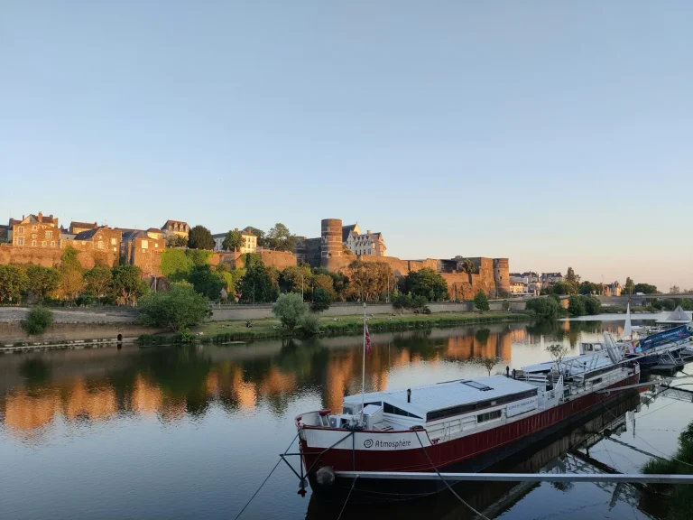 La Maine au pied des remparts du château d’Angers, avec une péniche amarrée, en fin de journée