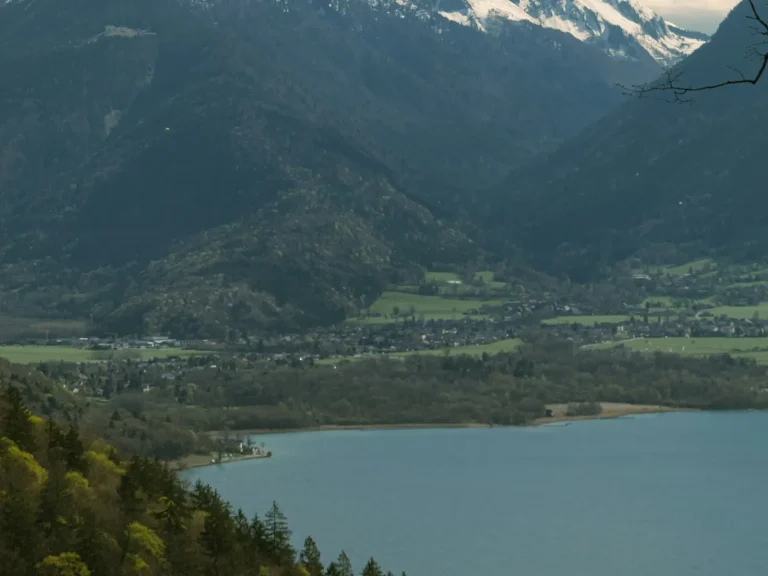Le lac d’Annecy vu depuis les pentes boisées, face aux montagnes et aux villages de la rive