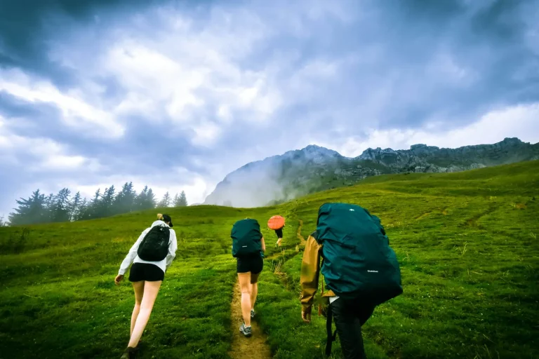 Quatre randonneurs sur un sentier d’alpage, sous les nuages, dans la montagne autour d’Annecy