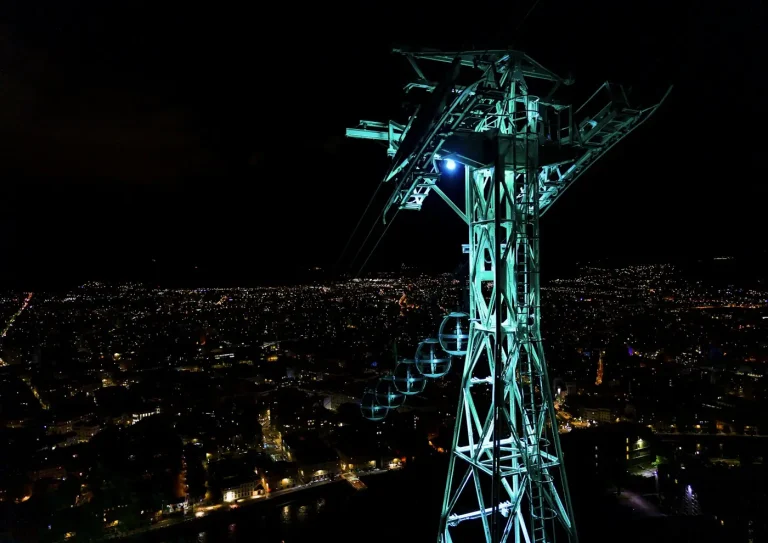Pylône illuminé du téléphérique au fort de la Bastille et lumières de Grenoble en contrebas, la nuit
