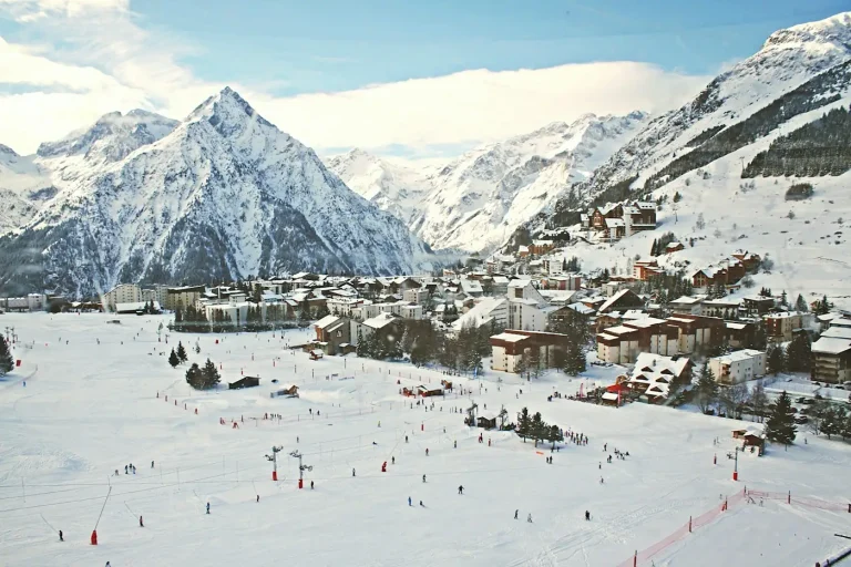 Skieurs sur les pistes enneigées au pied de la station des Deux Alpes et de ses sommets, en Oisans