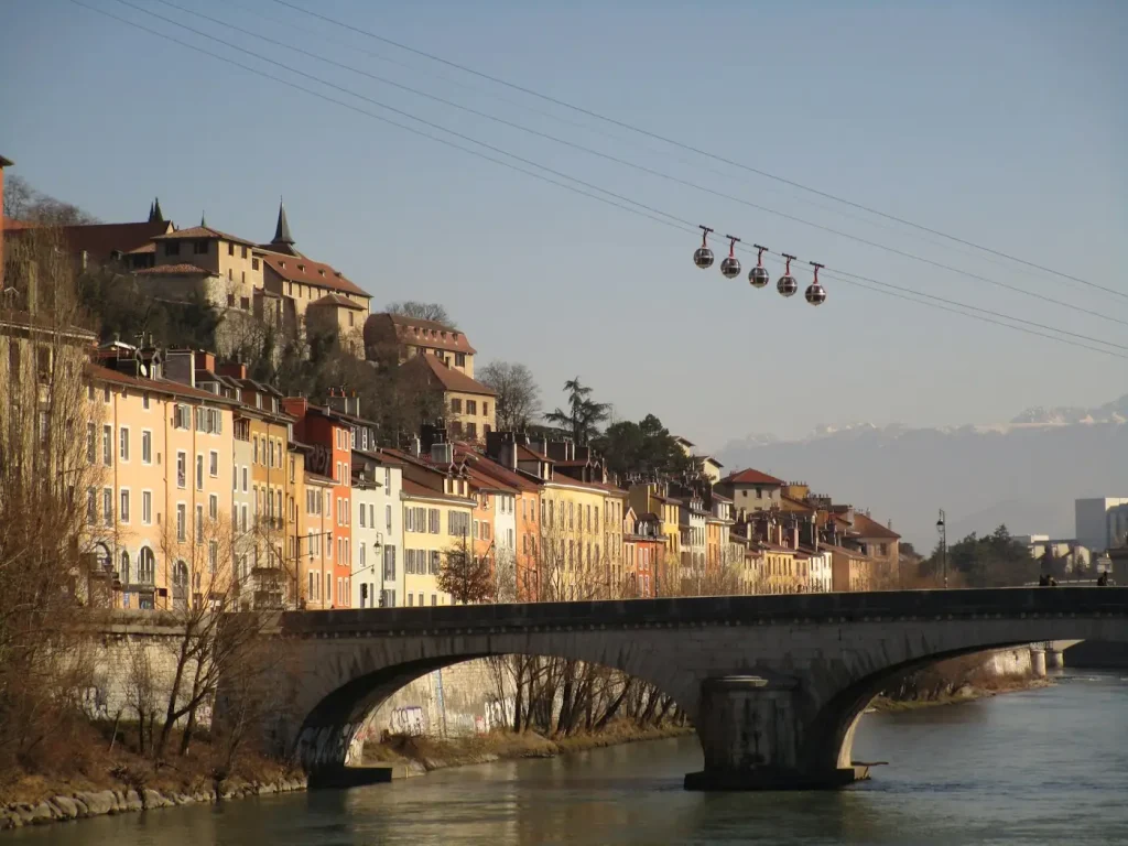 Les bulles du téléphérique de la Bastille au-dessus de l’Isère, de son pont de pierre et des façades colorées du quai, à Grenoble