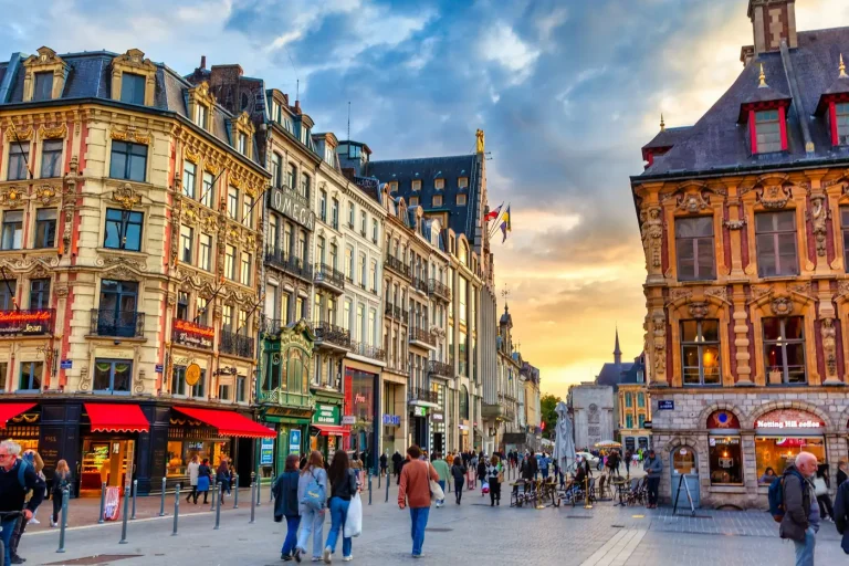 Façades ornées et passants dans une rue piétonne du centre de Lille, au coucher du soleil
