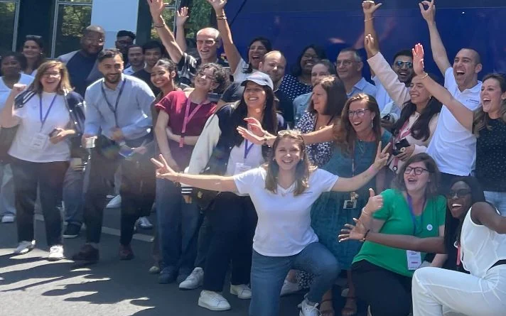 Participants du roadshow 2025 de Parthena, souriants et bras levés, réunis devant le car de la tournée