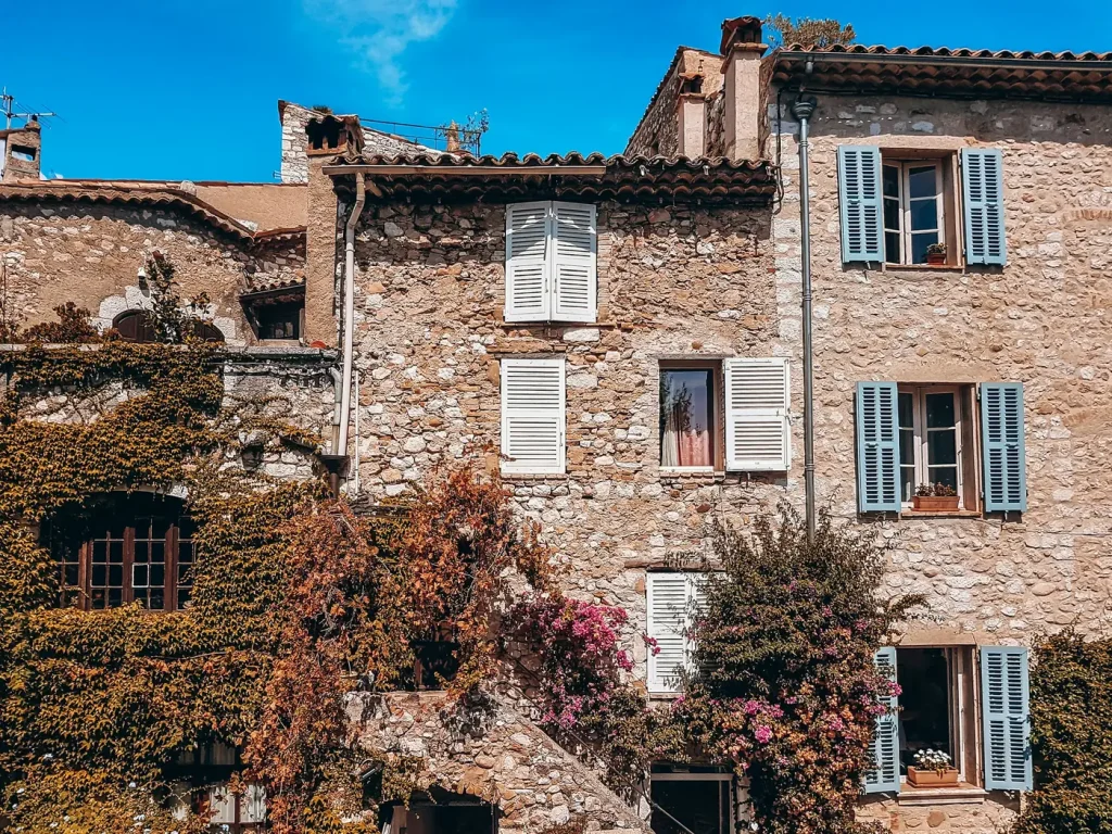 Maisons en pierre aux volets bleus, couvertes de lierre et de bougainvilliers, dans le village de Saint-Paul-de-Vence