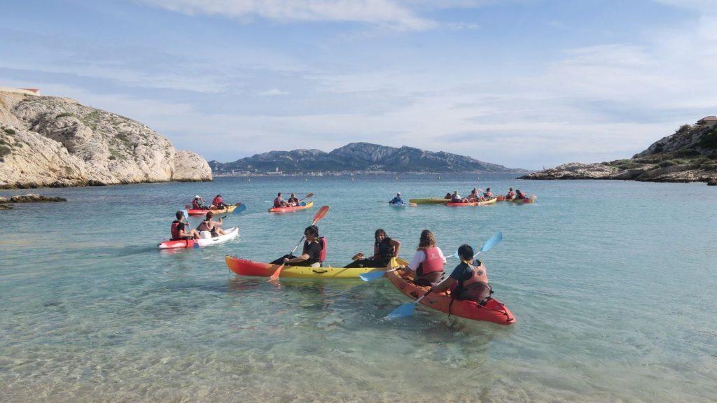Team building en kayak de mer au Frioul, au large de Marseille : collègues en kayaks biplaces dans une crique aux eaux turquoise