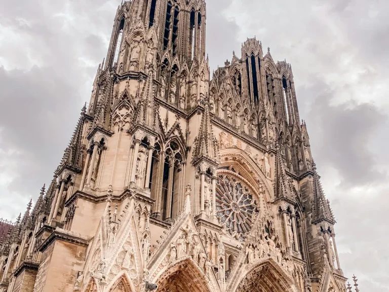 Les tours et la rosace de la façade de la cathédrale Notre-Dame de Reims, vues d’en bas, dans une lumière chaude