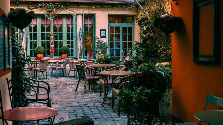 Cour pavée d’un restaurant du centre historique de Rouen, tables dressées entre les plantes et les façades colorées