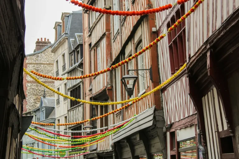 Guirlandes colorées tendues au-dessus d’une rue bordée de maisons à colombages, dans le Vieux-Rouen