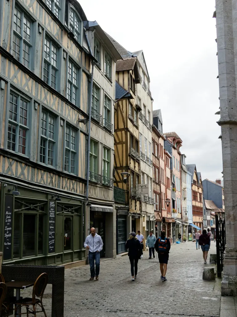 Passants dans une rue pavée bordée de hautes maisons à colombages, dans le centre historique de Rouen