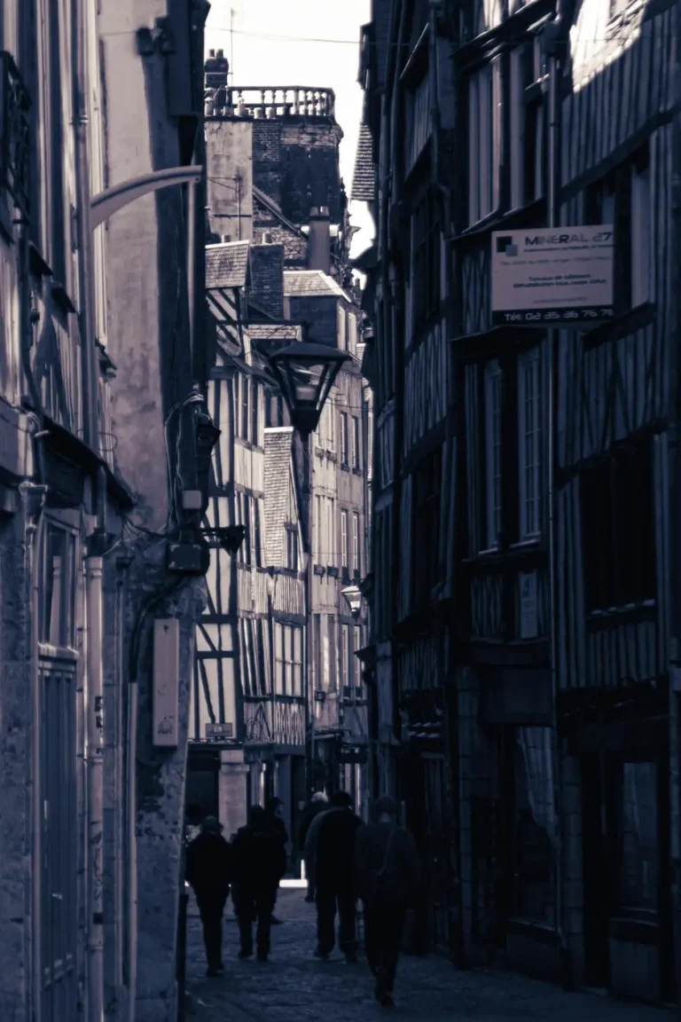 Passants dans une ruelle étroite bordée de maisons à colombages, dans le centre ancien de Rouen
