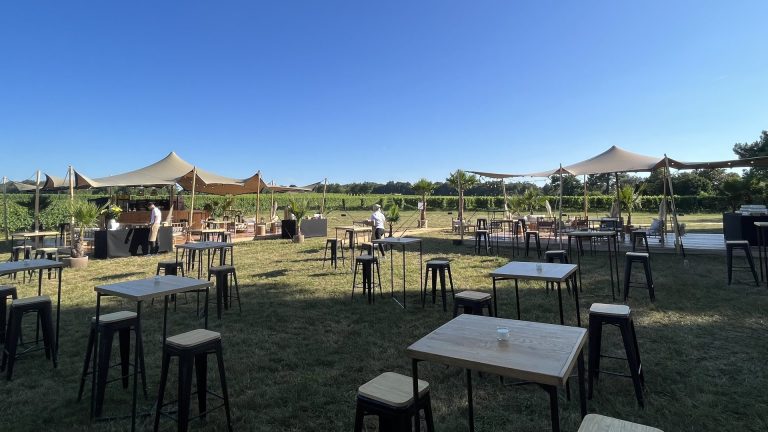 Espace convivial sous des tentes tendues face aux vignes, avec tables hautes et tabourets, pendant un séminaire organisé par Weevup au château Lafitte