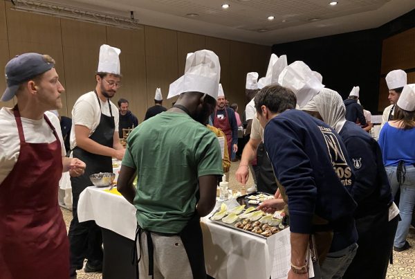 Participants du séminaire incentive de LIBON en toques blanches et tabliers, garnissant ensemble des plateaux sur de longues tables nappées pendant le cooking challenge organisé par Weevup au Pays basque