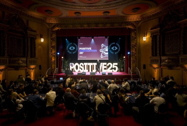 Plénière de la convention du Groupe Positive au Plaza Hotel de Bruxelles, organisée par Weevup : participants attablés face à la scène, à l'intervenant et au grand écran, dans une salle de spectacle aux décors dorés